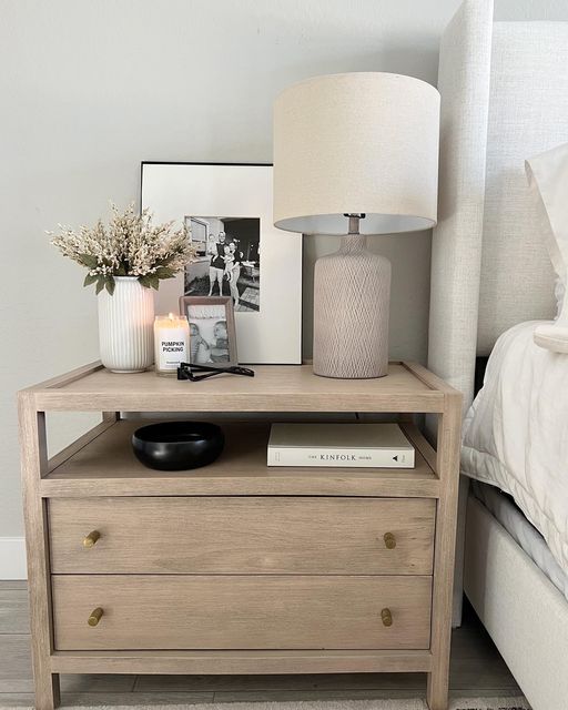 a nightstand with a lamp and pictures on it