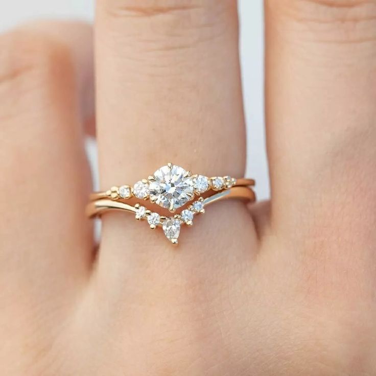 a woman's hand with a gold ring and two diamonds on top of it