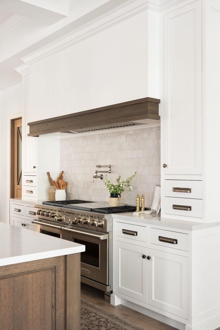 a kitchen with white cabinets and stainless steel stove top oven in the center, along with an area rug on the floor