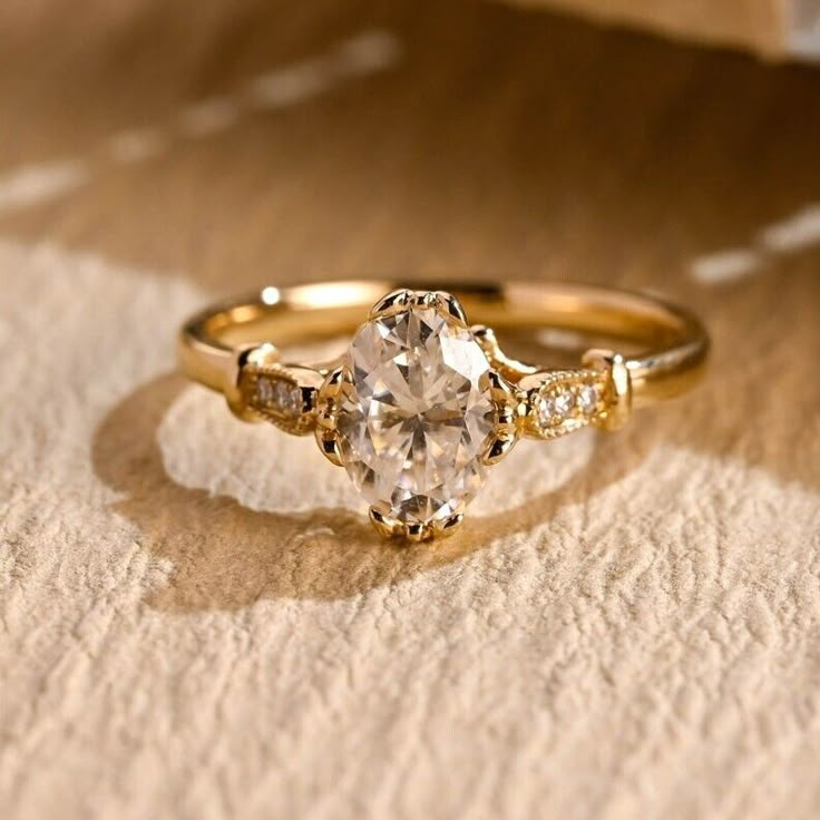 a close up of a gold ring with an oval cut diamond in the center and two smaller round diamonds on each side