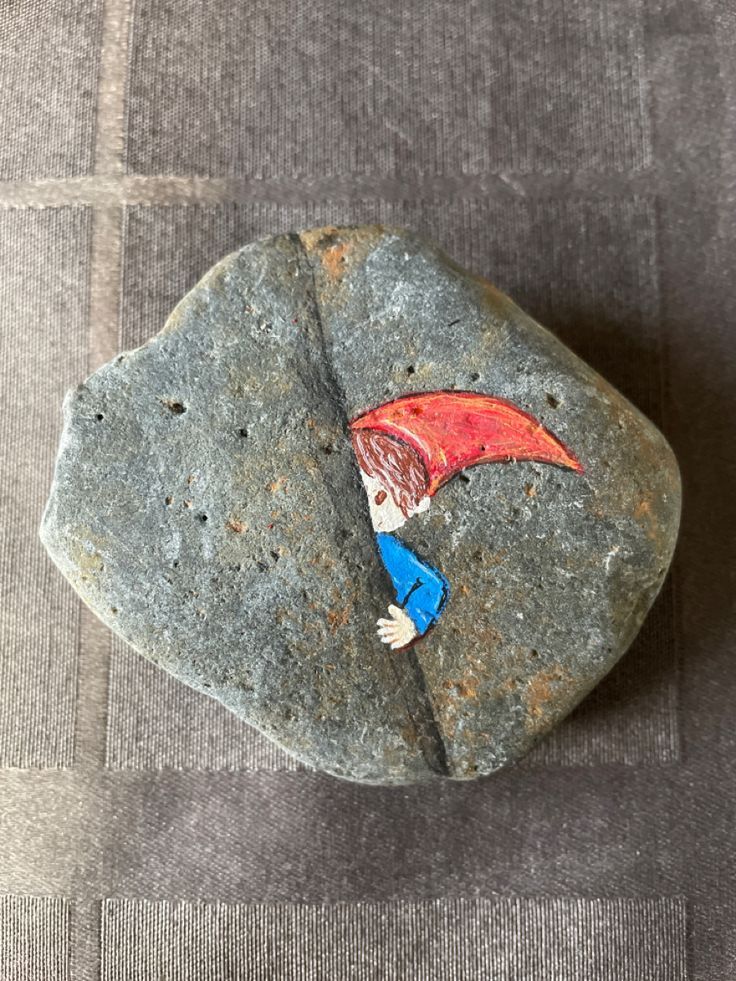 a rock with a drawing of a boy on it, sitting on a gray surface