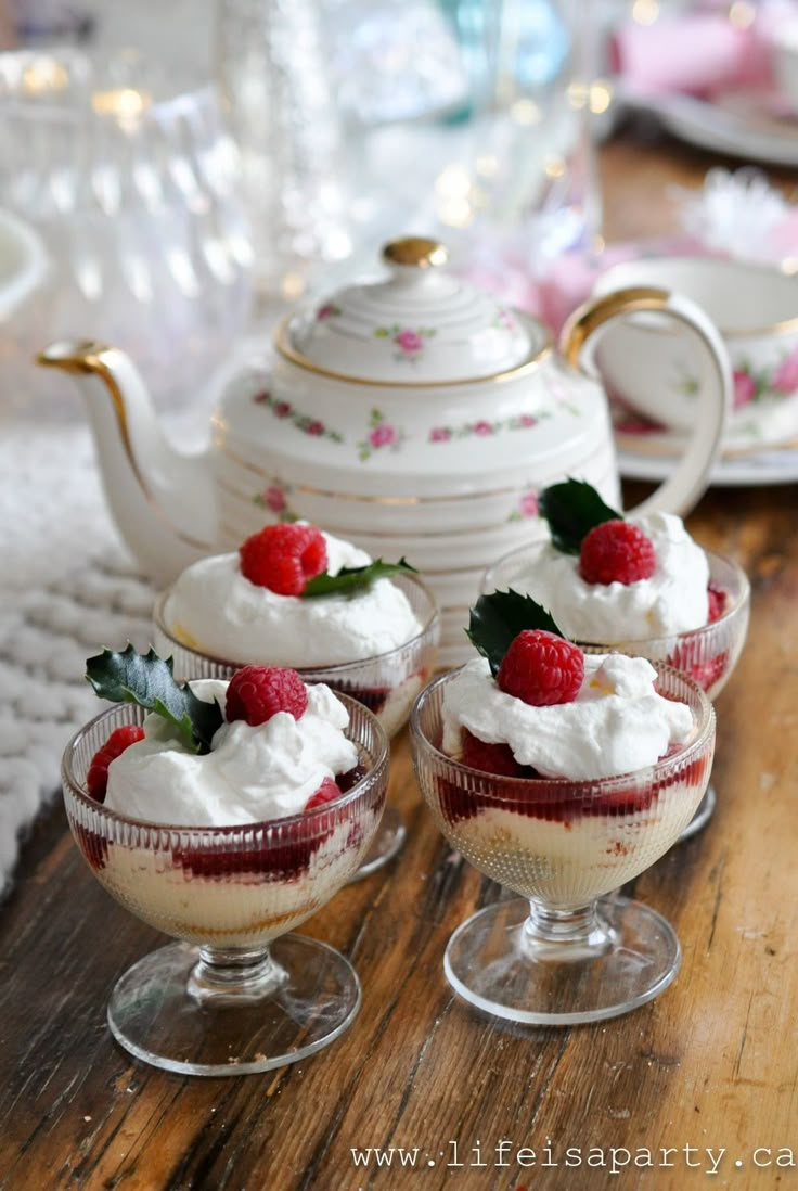 small desserts with whipped cream and raspberries in glass dishes on a wooden table