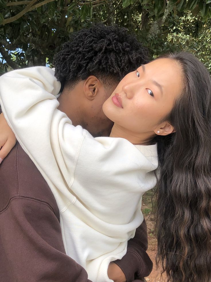 a man and woman embracing each other under a tree