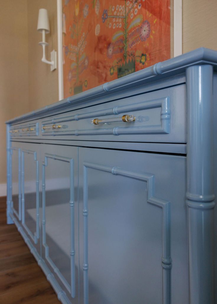 a large blue cabinet in a room with wood flooring and paintings on the wall