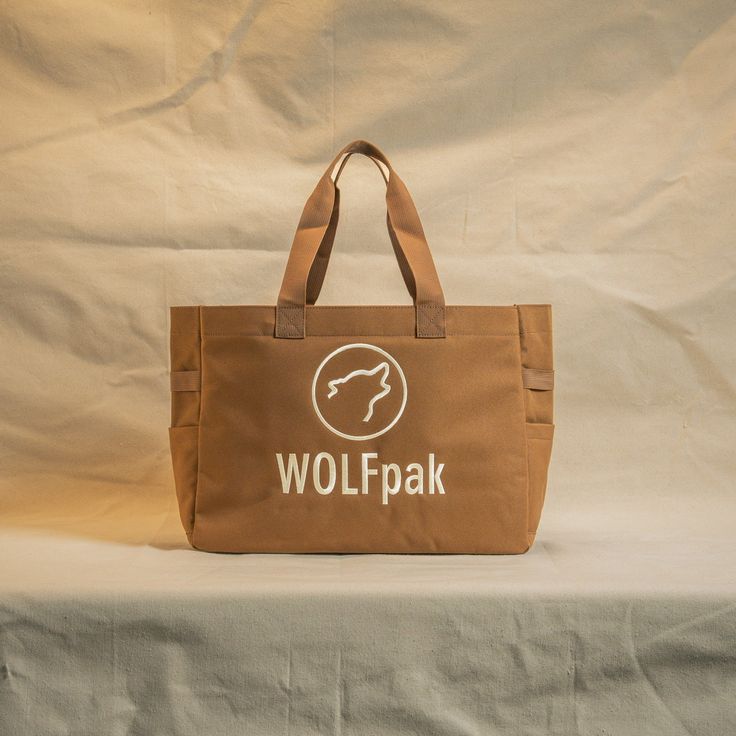 A High Quality, Lightweight Yet Durable Tote Bag by WOLFpak. This Tote Bag Is Extremely Practical For The Office, Gym, Beach and More! 20L Tote Bag 17in (43cm) W x 13in (33cm) H x 6in (14cm) Waterproof Surface Oxford 1000D Polyester Dual Exterior Side Pockets Hand Carrying Straps or Over the Shoulder Branded Embroidery Logo Molle Webbing Easy Clean Polyurethane Lining Protective Inside Computer Sleeve 17in x 10in (Fits 16” Mac Pro) Inside Zipper Pocket (2) Mesh Card Pockets Eco-friendly Lightweight Brown Beach Bag, Brown Logo Tote Shoulder Bag, Eco-friendly Brown Shoulder Bag With Removable Pouch, Brown Solid Color Tote Bag, Eco-friendly Outdoor Tote Shoulder Bag, Molle Webbing, Mac Pro, Credit Card Processing, Computer Sleeve