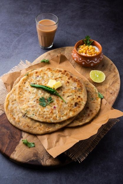 two flat breads on a wooden plate with a glass of milk and some garnishes