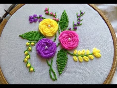 a close up of a embroidery on a hoop with flowers and leaves in the center