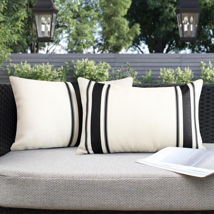 two black and white pillows sitting on top of a couch next to a lamp post