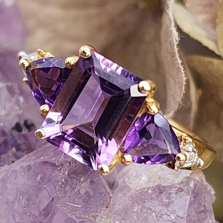 * Fall in love with this classic amethyst ring! The emerald cut amethyst is a deep purple and the nice size of the stone makes a statement all of its own. The center stone has two, trillion cut amethysts that flank either side and two diamonds that give the ring extra sparkle. This ring is elegant and would make a wonderful gift for someone with a February birthday, or anyone with a love for this beautiful gemstone! *  This ring weighs 1.8  grams. This ring tested positive for 14K gold here in o Luxury Yellow Gold Amethyst Ring, Classic Luxury Multi-stone Amethyst Ring, Luxury Multi-stone Gold Amethyst Ring, Luxury Multi-stone Amethyst Ring In Yellow Gold, Luxury Purple Amethyst Ring, Rectangular Shape, Purple Amethyst Ring For Anniversary, Luxury Purple Amethyst Rectangular Ring, Luxury Purple Rectangular Amethyst Ring, Luxury Amethyst Ring Emerald Cut