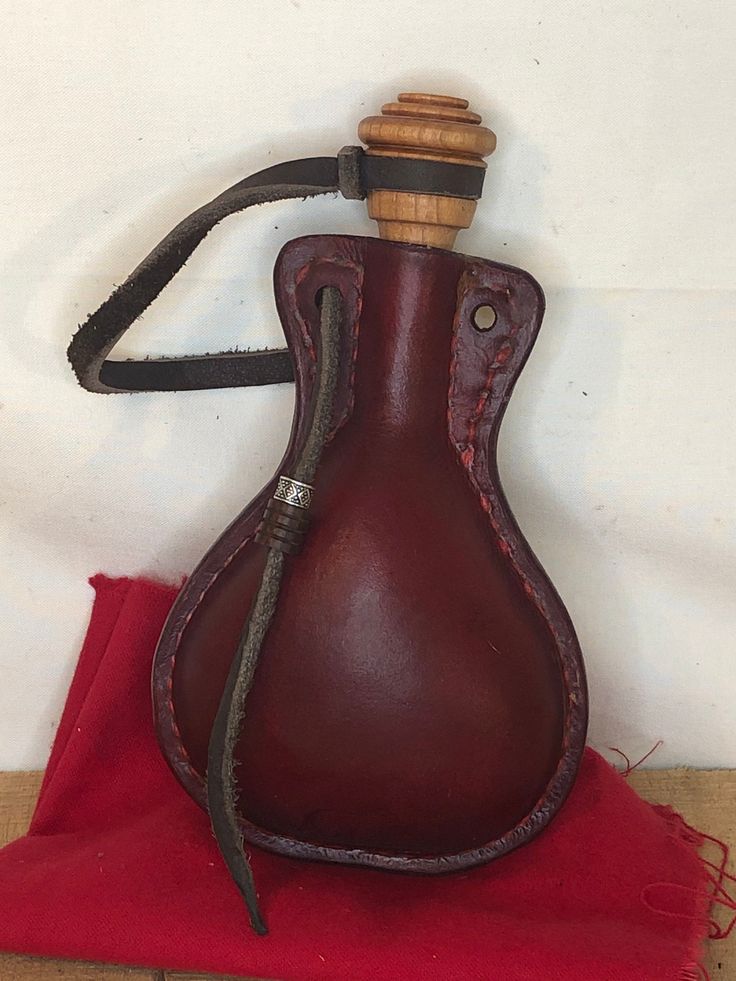 a brown leather vase with a wooden handle