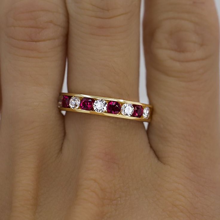 a woman's hand with a gold ring and three stones on it, all in different colors