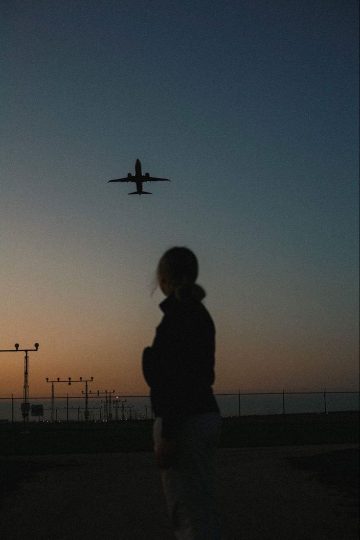 a person watching an airplane fly in the sky