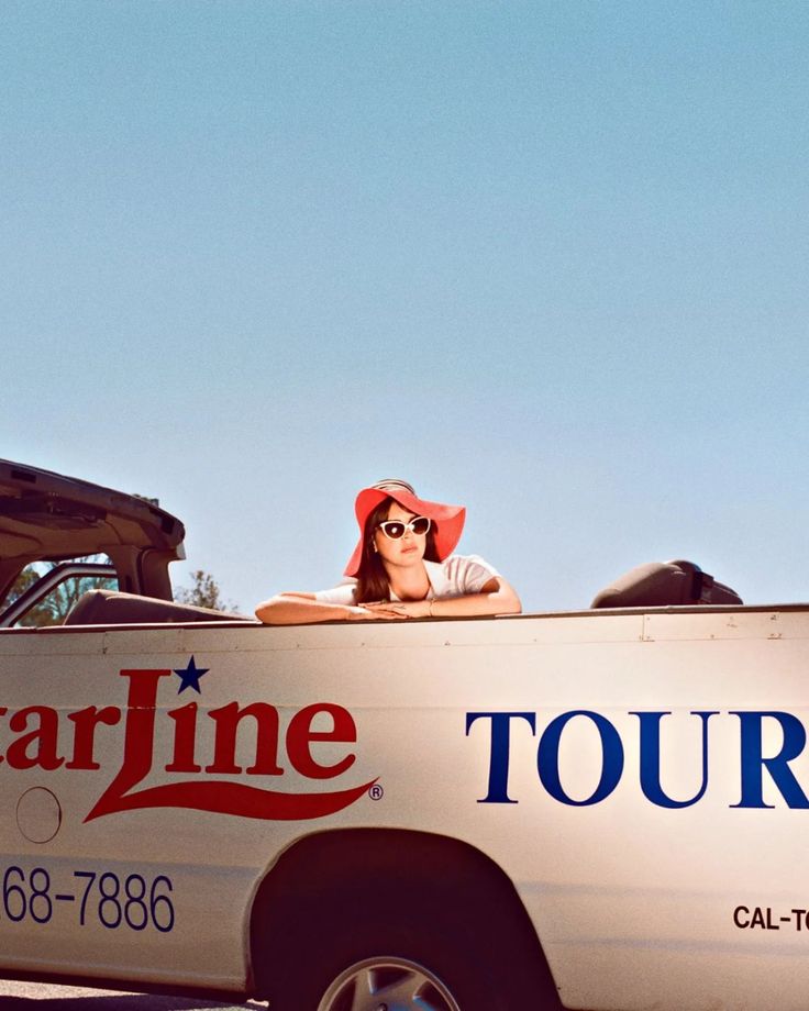 a woman sitting in the back of a truck with a tour sign on it's side