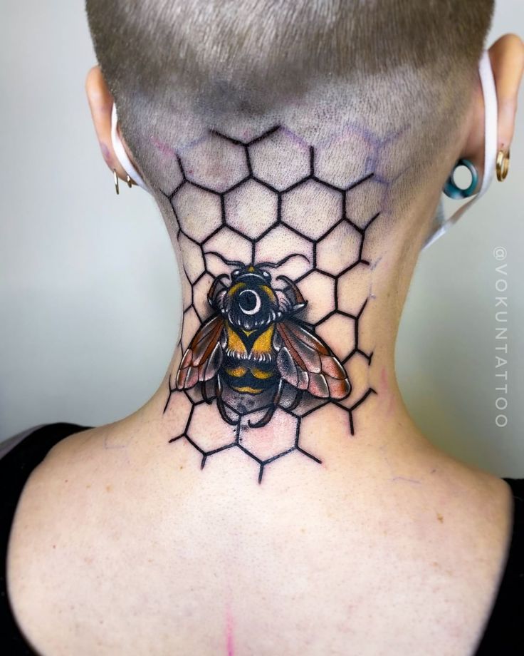 a woman's neck with a bee tattoo on the back of her head,