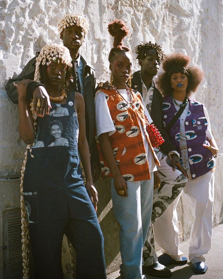 four people standing next to each other in front of a white wall with an afro hairstyle