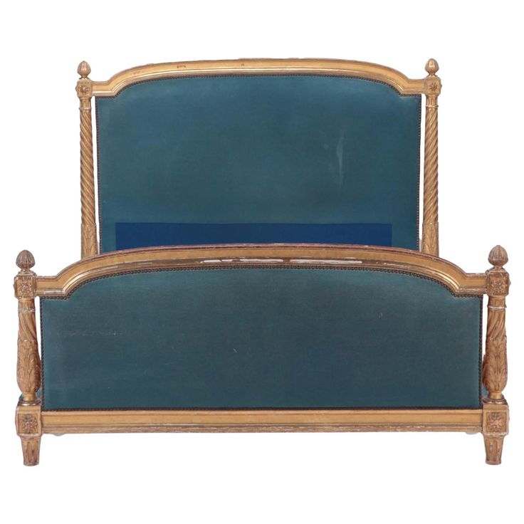 an antique bed frame with blue upholstered headboard