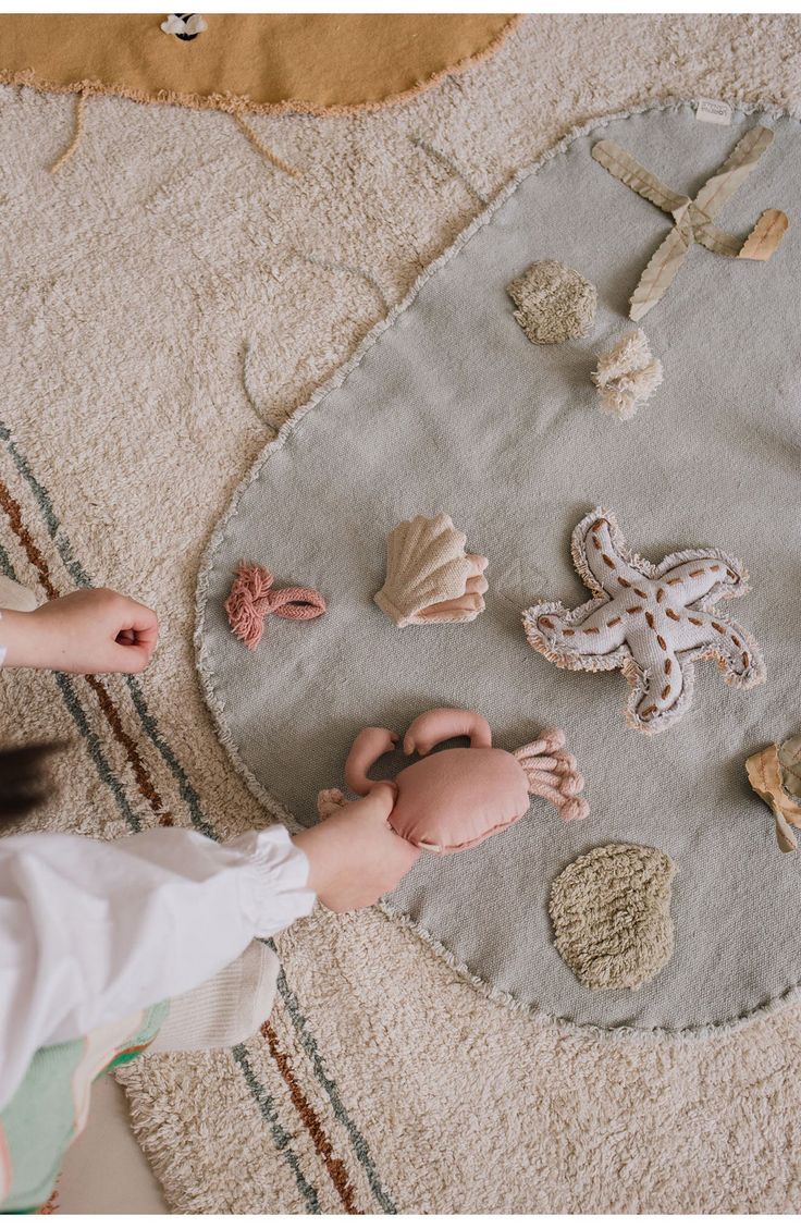 a child is playing with seashells on the floor in front of a rug