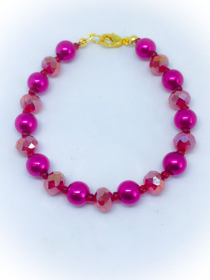 a bracelet with pink beads and gold clasp on a white background, the bead is made out of glass