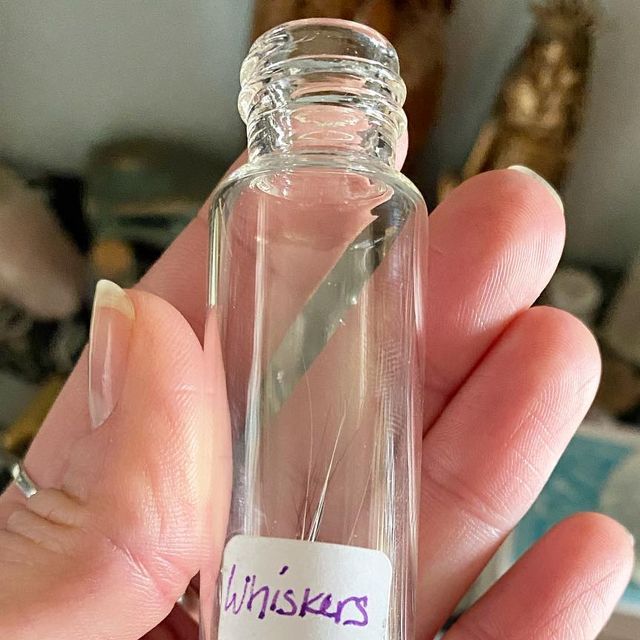 a person holding a small glass bottle with writing on the bottom and purple ink in it