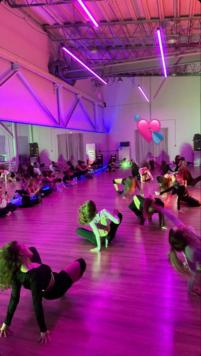 a group of people are dancing in a large room with bright lights on the ceiling