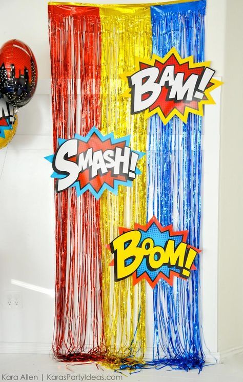 some balloons and streamers in the shape of comic book characters are hanging on a wall