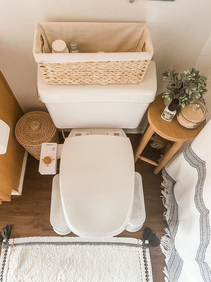 a white toilet sitting in a bathroom next to a wooden table with a basket on it