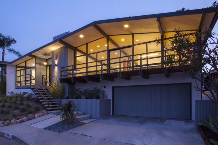 a modern house is lit up at night with lights on the roof and stairs leading to the upper level