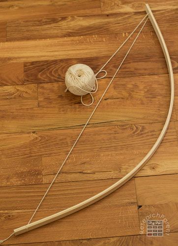 a ball of yarn sitting on top of a wooden floor next to a bow and arrow