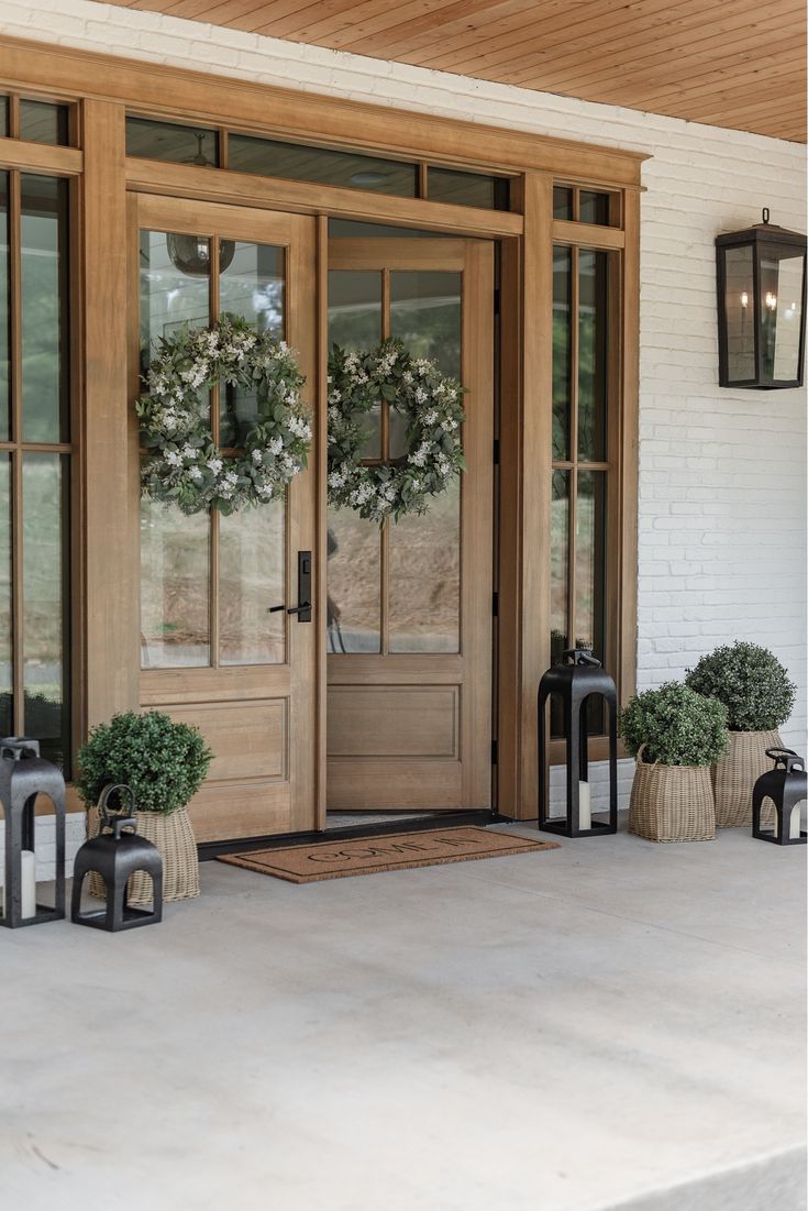 the front door is decorated with wreaths and lanterns