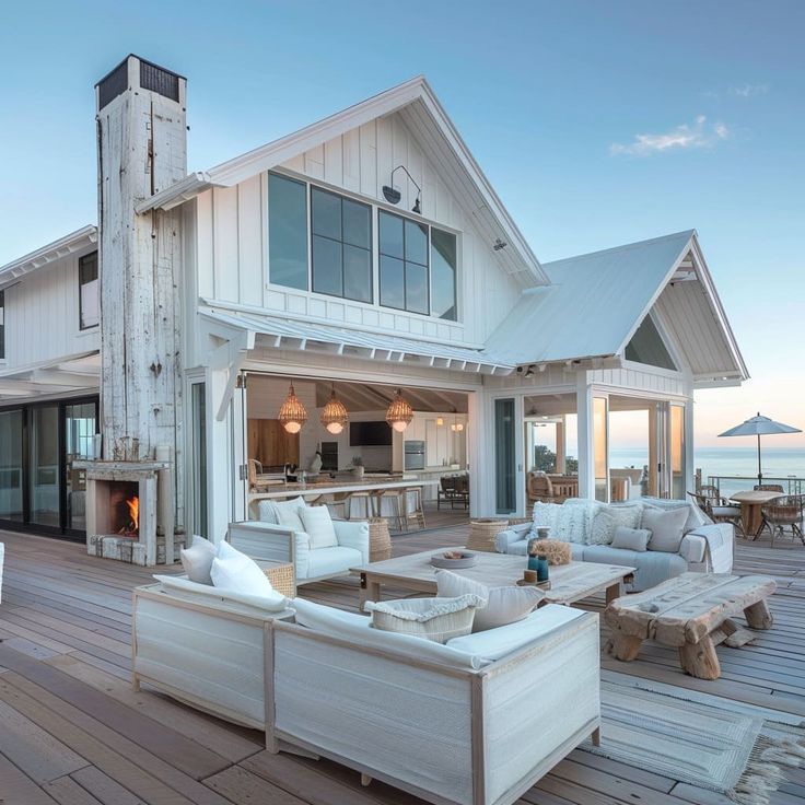 an outdoor living area with couches and tables on a wooden deck overlooking the ocean