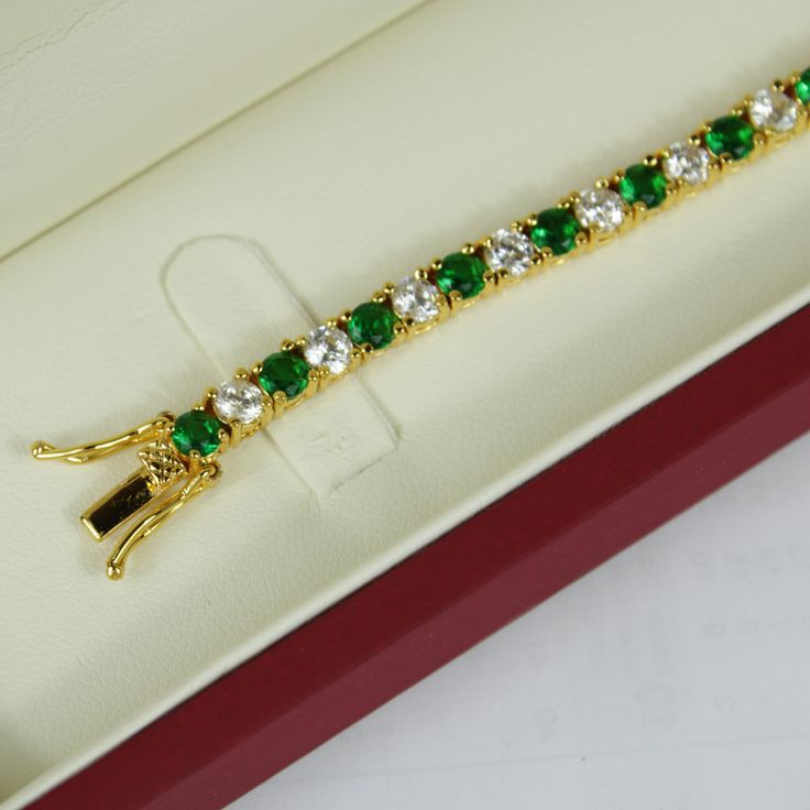 YELLOW GOLD FINISH Created Diamond Round Cut Green Emerald Tennis Bracelet  This green emerald and created diamond bracelet is made in the style of a tennis bracelet with a circular fine finish, with created green emerald gems. It is a bracelet sure to provide you with style comfort. The green emerald gems are studded with small diamanté's carved to perfection, offering a great sheen and pristine look.  Round diamonds are traditionally the first and most popular diamond that's given as a symbol of commitment. They have a classic uniform and symmetrical shape that consists of 58 facets, which qualifies them a brilliant cut. The faceting on round cut diamonds also makes colour and inclusions appear better than in other fancy shapes. In fact, these stones are so beloved that over 50% of all d Luxury Green Tennis Bracelet For Formal Events, Luxury Green Round Cut Jewelry, Classic Gemstone Tennis Bracelet Gift, Classic Gemstone Tennis Bracelet As Gift, Luxury Emerald Tennis Bracelet As Gift, Classic Green Bracelet With Brilliant Cut, Luxury Emerald Tennis Bracelet Gift, Green Cubic Zirconia Tennis Bracelet For Formal Occasions, Formal Green Cubic Zirconia Tennis Bracelet