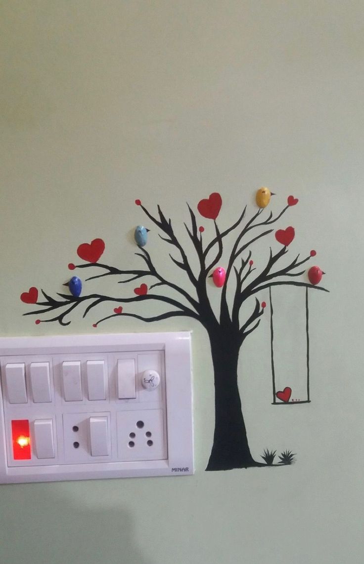 an electrical outlet box with hearts on it and a tree painted on the wall behind it