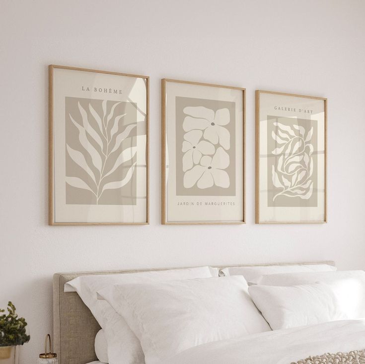 three framed pictures hang above a bed in a bedroom