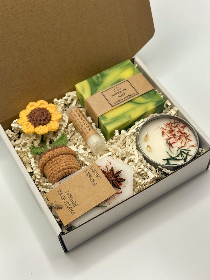 an open box containing soaps, candles and other decorative items on white table top