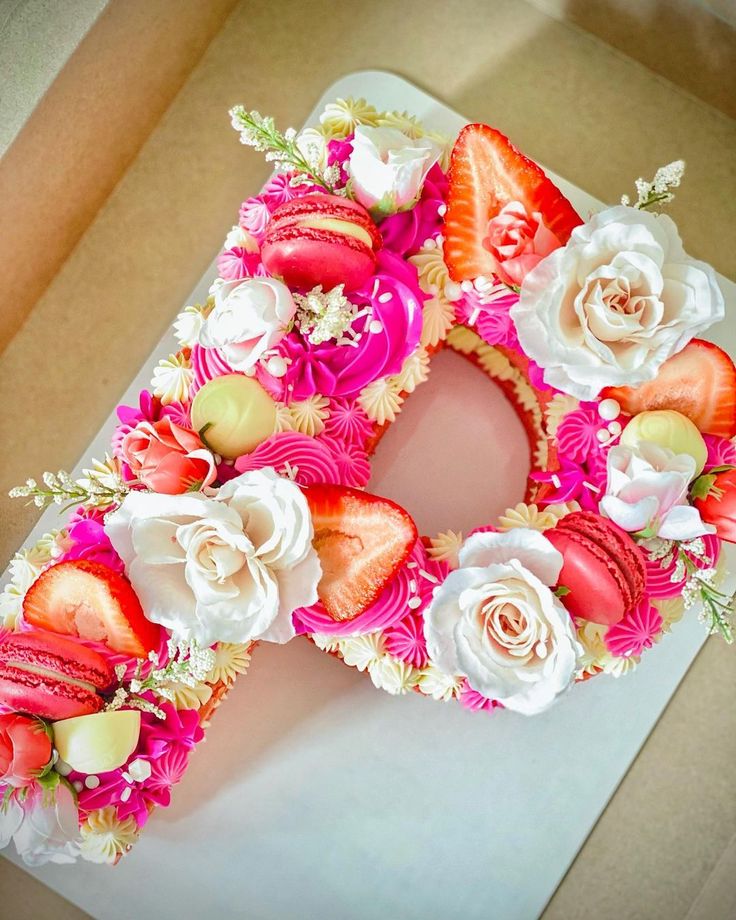 the letter o is made out of flowers and strawberries on top of a cake