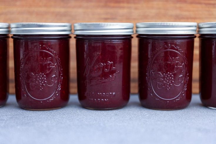 four jars filled with red liquid sitting next to each other