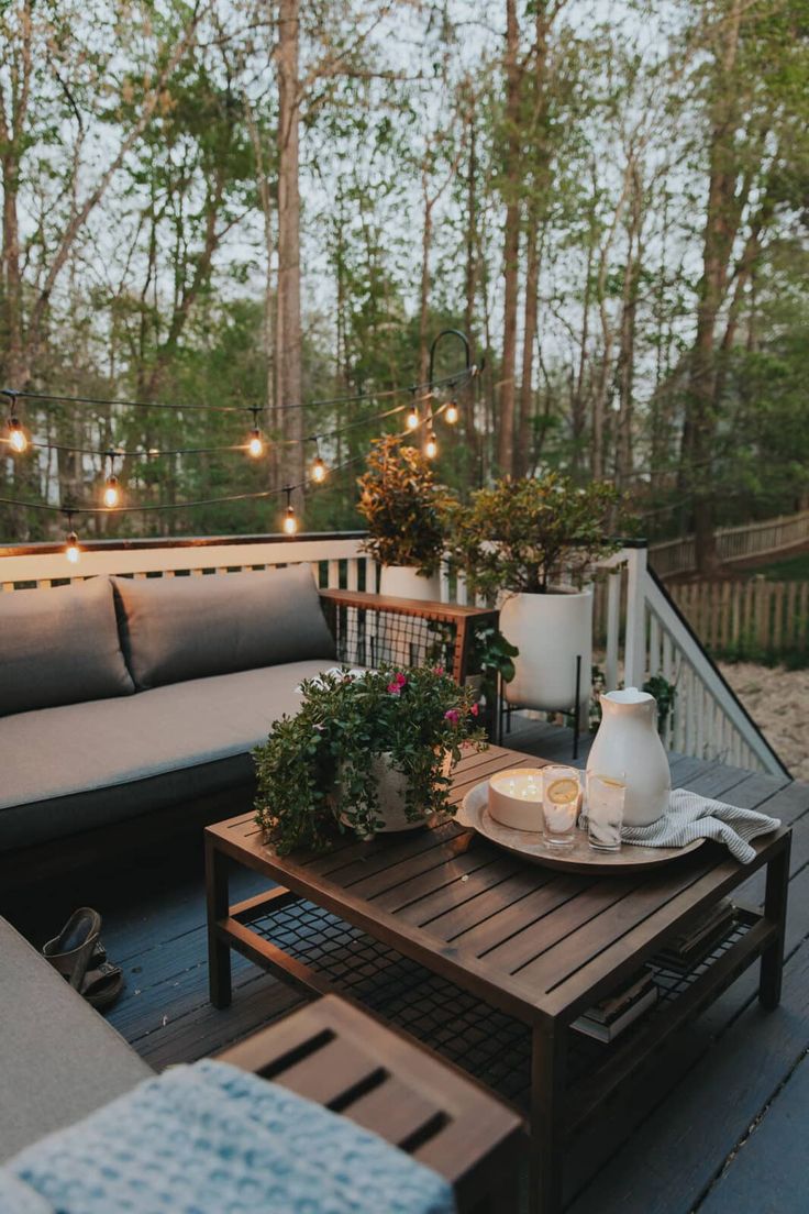 a table with plates and cups on top of it next to a couch in front of some trees