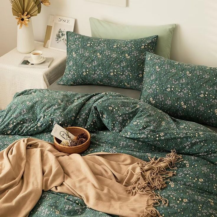 an unmade bed with green and white floral bedspread on top of it