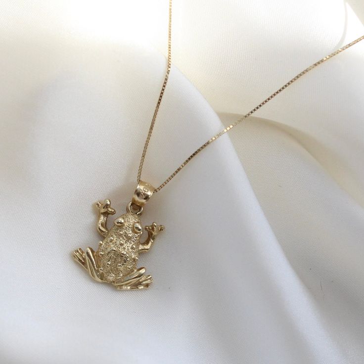 "14k Gold Frog Necklace Charm, Animal lovers Jewelry, 14K Gold 2-D Frog Necklace, Yellow Gold Frog Necklace Charm, Animal Lovers Gift, Can be worn with other necklaces, great for layers. A Perfect 14K Gold gift. . . . * Pendants Measurements With Bail: ((20 x 16 mm) * Chain is included ( 1MM Box Chain) * Stamp: Real 14k Gold * Never gold filled or plated * Hypoallergenic * Water Resistant * Scratch Resistant * Packaged With Free Gift Box . . . If you have any questions, just hit the \"Message the Seller\" button ( bottom right of the page) and we will get back to you within a few hours. . . .  IF YOU WISH TO BUY THE PENDANT ALONE, COPY AND PASTE THE LINK BELOW IN A NEW TAB TO FIND THAT LISTING https://www.etsy.com/listing/1235840487/14k-gold-turtle-necklace-charm-sea? . . . Mailed in a cut Tiana Necklace, The Princess And The Frog Jewelry, Gold Frog Necklace, Frog Pendant, Cat Necklace Gold, Frog Necklace, Turtle Necklace, Gold Gift, Game Dresses