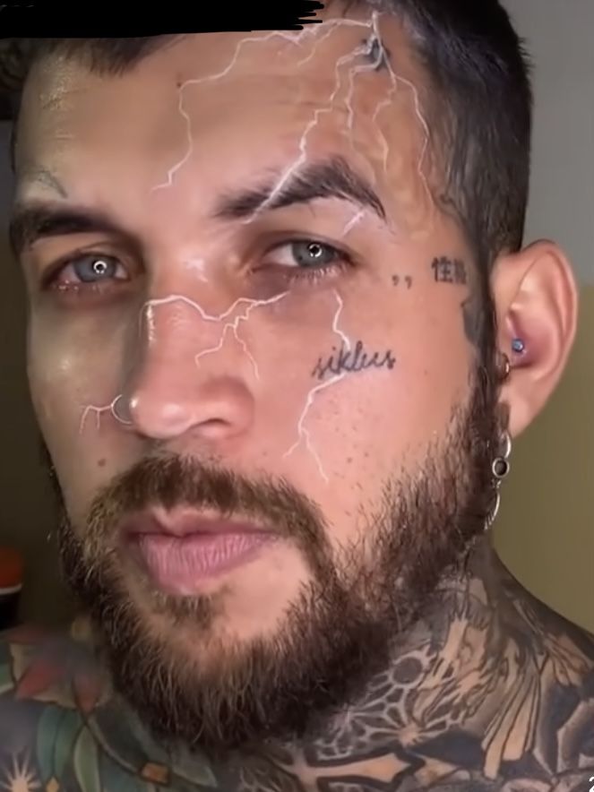 a man with tattoos and piercings on his face is looking at the camera while he has