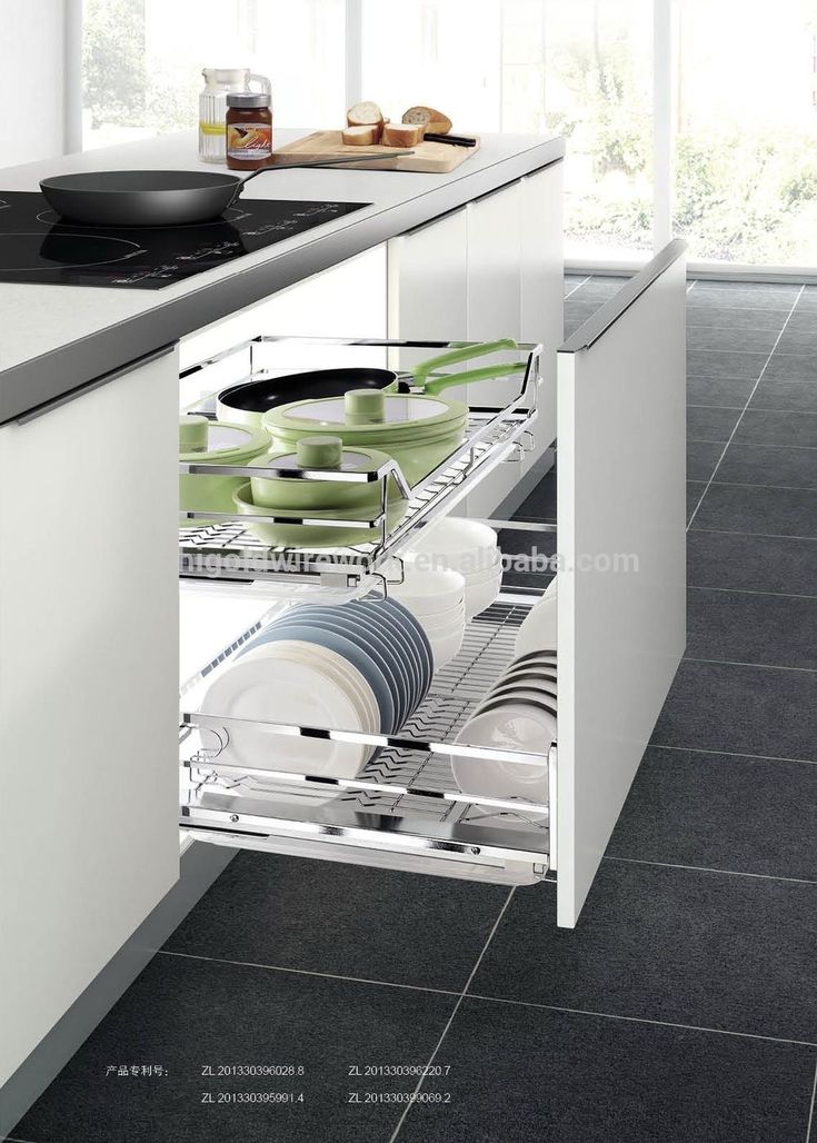 an open drawer in the middle of a kitchen with plates and bowls on it's side