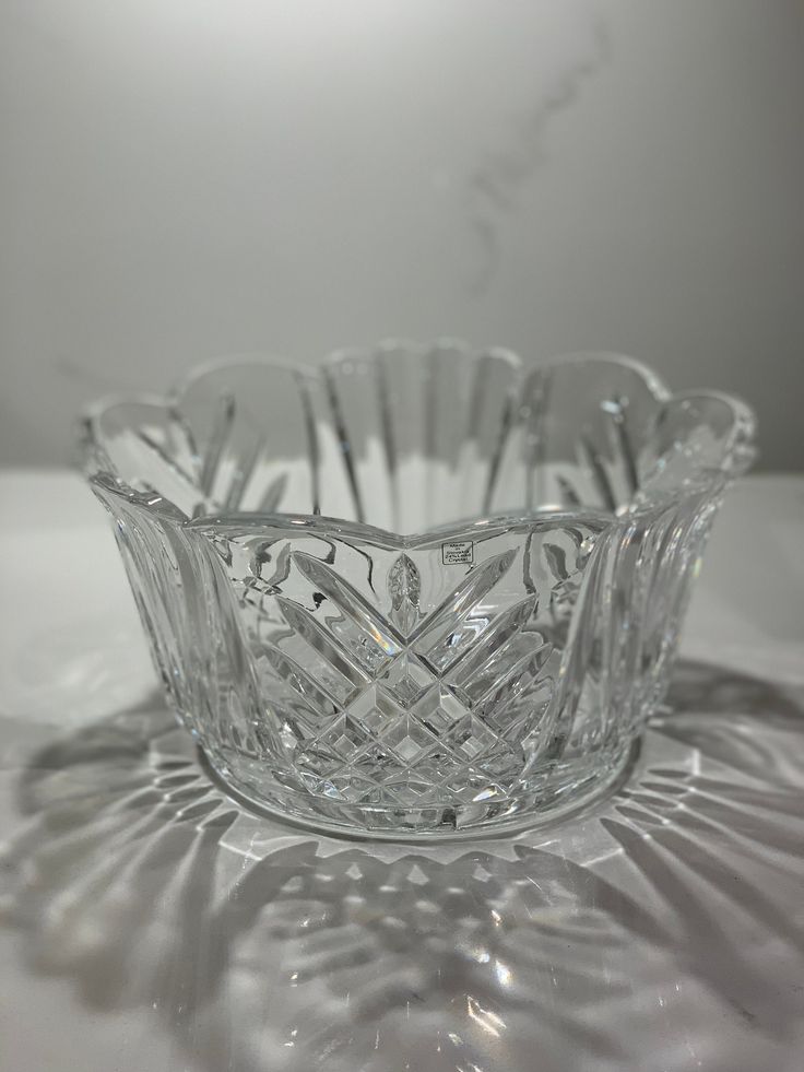 a clear glass bowl sitting on top of a white table covered in shadow and light