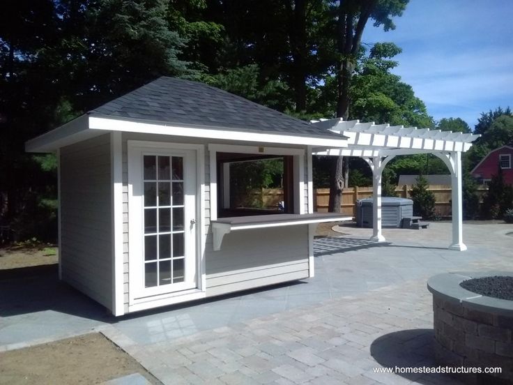 a small white gazebo sitting on top of a brick patio next to a fire pit