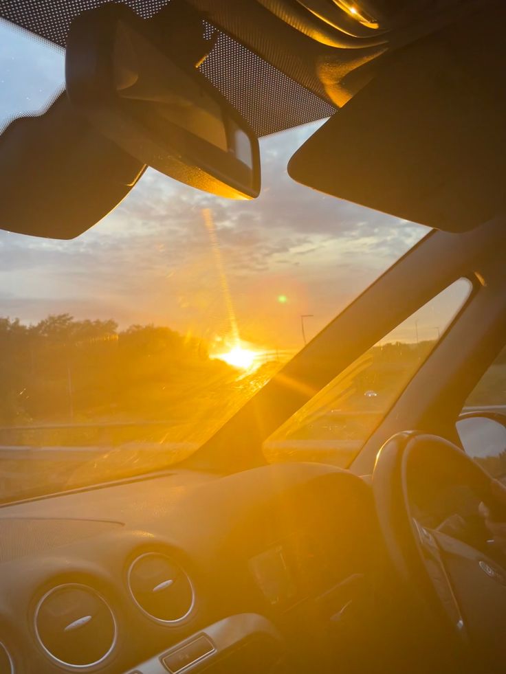 the sun is setting behind some cars