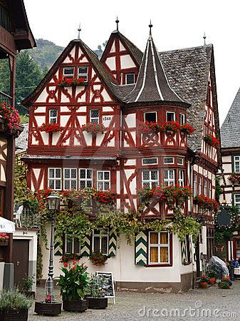 an old building with red and white paint on it's side in the middle of town