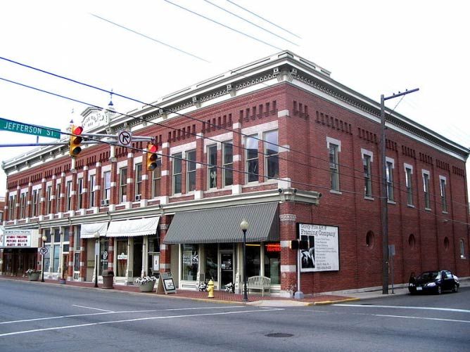 an old red brick building on the corner of a street in front of a traffic light