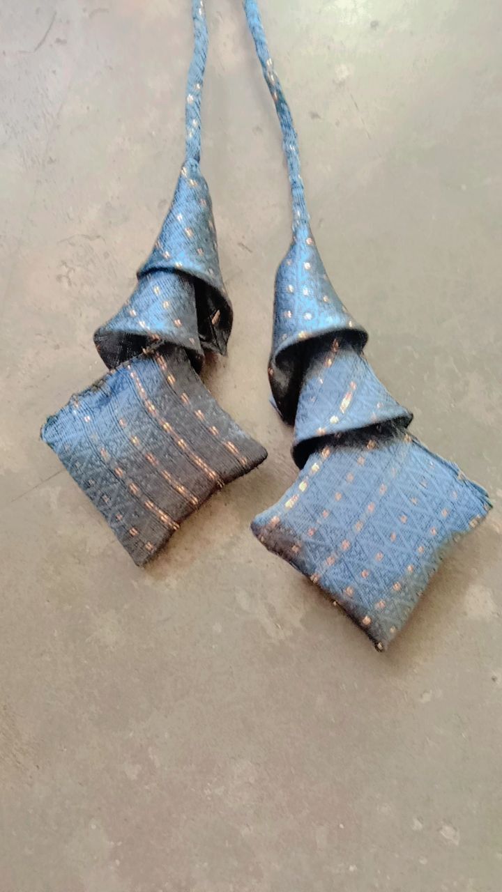 two pieces of blue fabric with gold dots on them, tied together and sitting on the floor