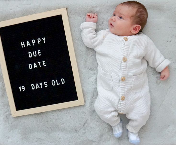 a baby laying next to a sign that says happy duee date 19 days old