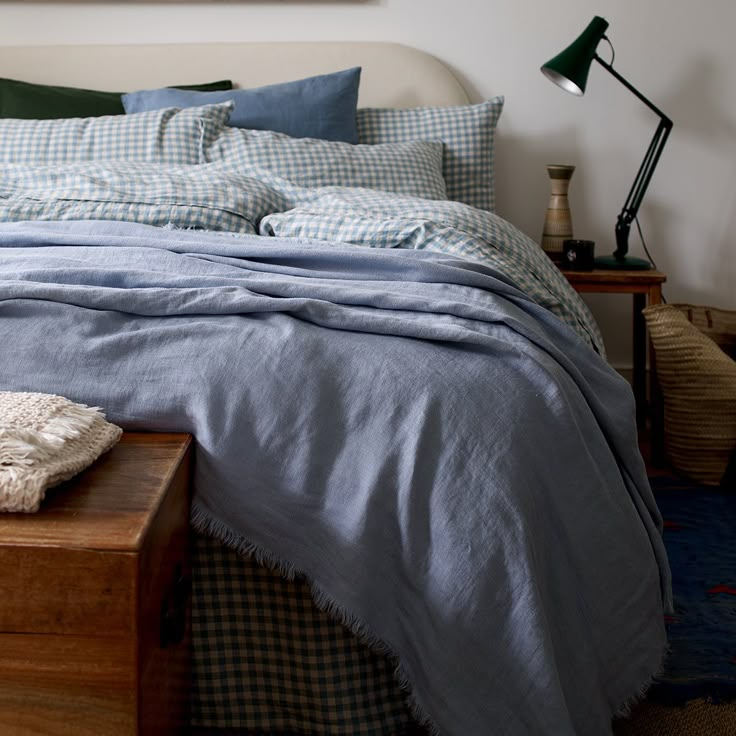 a bed with blue sheets and pillows in a bedroom