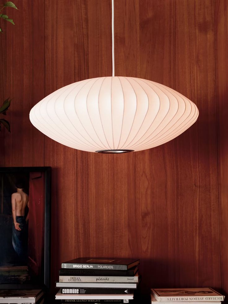 a white light hanging from a wooden wall next to some books and a framed photograph